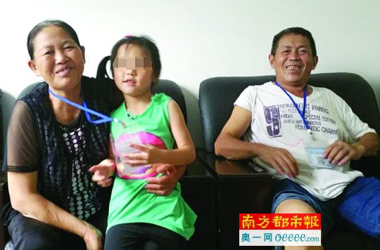 胡阿姨抱着点点，老公在一旁，点点看到有人拍照很害羞。